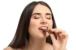 Eine Frau isst ein Stück Schokolade Eine Frau isst ein Stück Schokolade