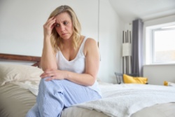 Depressive Frau sitzt lustlos auf dem Bett