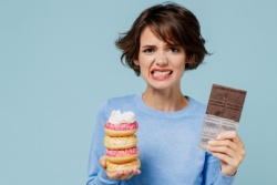 Gestresste Frau mit Schokolade und Kuchen