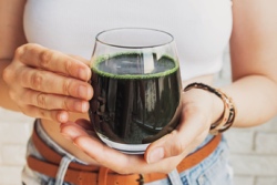 Frau h&auml;lt Glas mit Spirulina in der Hand