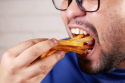 Mann nimmt einen gro&szlig;en Bissen Pommes