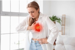 Junge Frau beugt sich vorn&uuml;ber und umklammert ihr Herz