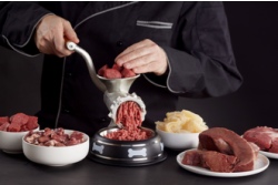 Mann, umgeben von rotem Fleisch, verwandelt Hackfleisch