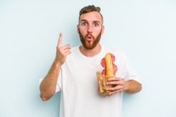 Junger Mann isst ein Salami-Sandwich