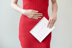 Eine Frau mit Menstruationsschmerzen hält sich den Bauch Eine Frau mit Menstruationsschmerzen hält sich den Bauch