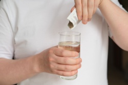 Ein Mann gibt Elektrolyte in ein Glas Wasser Ein Mann gibt Elektrolyte in ein Glas Wasser