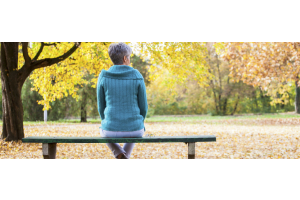 Frau im Herbst auf einer Bank im Park