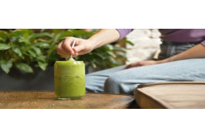 Die Frau nimmt einen Schluck von ihrem Moringa-Smoothie.