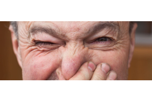 Ein alter Mann hält sich die Nase zu.