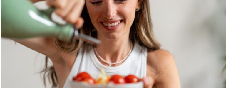Frau gießt natives Olivenöl extra über ihren gesunden Salat