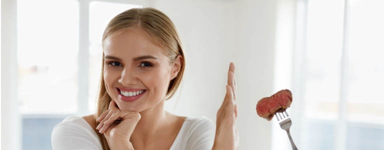 Eine Frau weist ein Stück Fleisch mit der Hand zurück.