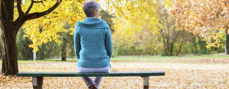 Frau im Herbst auf einer Bank im Park