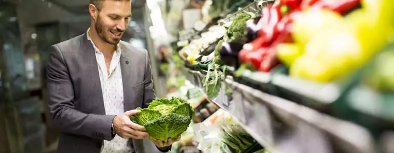 Mann mit grünem Gemüse im Supermarkt