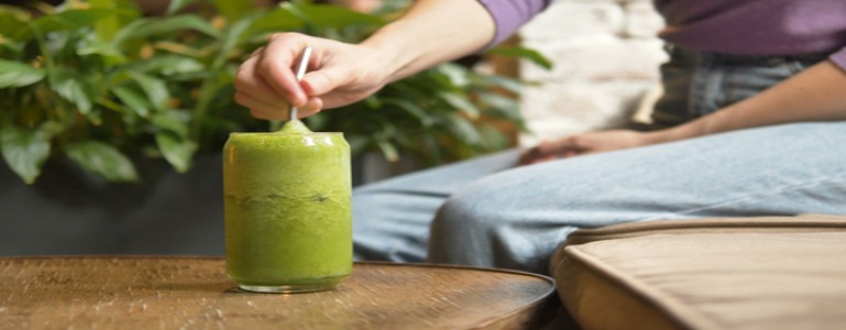 Die Frau nimmt einen Schluck von ihrem Moringa-Smoothie.