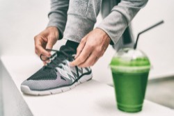 Ein Mann bindet sich die Schnürsenkel und trinkt einen Smoothie mit Moringa. Ein Mann bindet sich die Schnürsenkel und trinkt einen Smoothie mit Moringa.