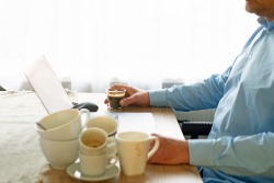 Mann mit vielen leeren Kaffeetassen neben sich auf seinem Schreibtisch Mann mit vielen leeren Kaffeetassen neben sich auf seinem Schreibtisch