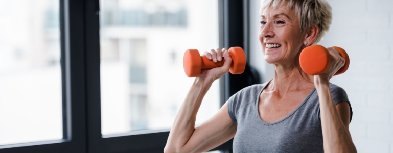 Frau mittleren Alters mit Gewichten in der Hand