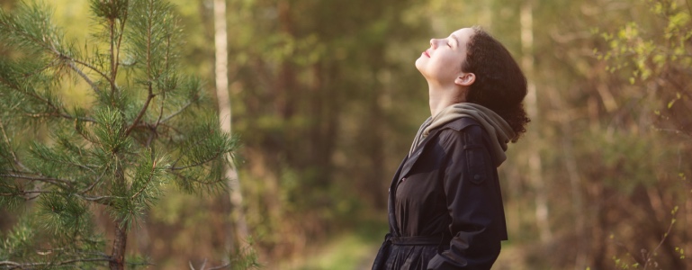 Frau atmet die frische Waldluft ein