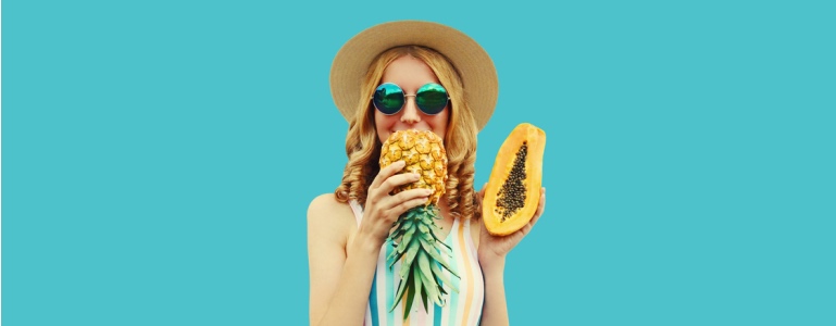 Die Frau hält Ananas und Papaya in ihren Händen