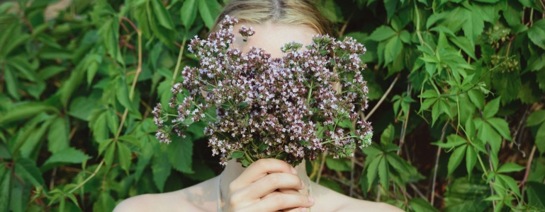 Frau mit einem Bund Oregano vor dem Gesicht