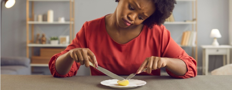 Frau isst mit Mühe ein kleines Stück Essen