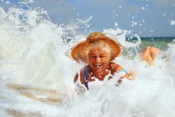 Eine l&auml;chelnde &auml;ltere Frau spielt in den Wellen