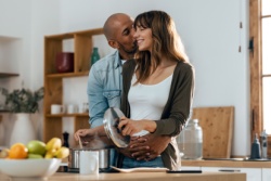 Der Mann steht hinter der Frau und gibt ihr einen Kuss auf die Wange. Der Mann steht hinter der Frau und gibt ihr einen Kuss auf die Wange.