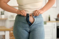 Frau kann den Knopf ihrer Hose nicht schlie&szlig;en