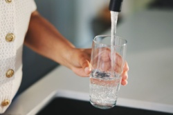 Eine Frau schenkt sich ein Glas Wasser ein.