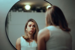 Die Frau blickt unglücklich in den Spiegel. Die Frau blickt unglücklich in den Spiegel.