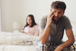 Der Mann sitzt zusammengesunken auf dem Bett und stützt sich auf seinen Arm. Der Mann sitzt zusammengesunken auf dem Bett und stützt sich auf seinen Arm.